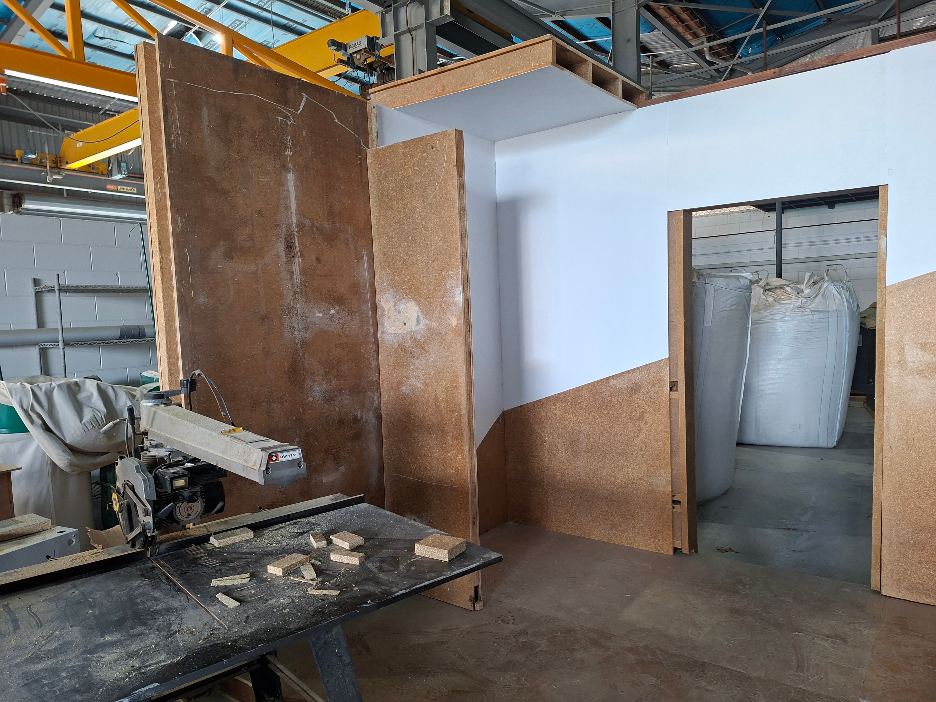 Hemp panel sheets in an Australian workshop — engineered hemp panel material under development for the Joey60 Hemp Edition, with a panel-cutting station in the foreground
